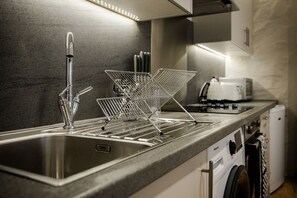 Uma cozinha moderna com uma pia de aço inoxidável, um escorredor de arame e uma máquina de lavar louça embutida.
