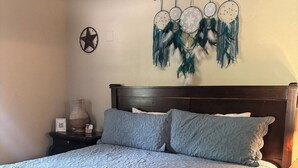 A bedroom with a large bed, a nightstand, a wall-mounted dreamcatcher, and a star decoration.