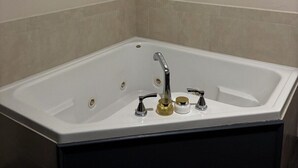 A modern bathroom with a freestanding bathtub, a handheld showerhead, and a wall-mounted faucet.