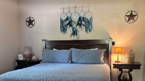 A bedroom with a wooden bed, a nightstand, a lamp, and a wall decoration.