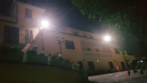 A building with a lighted entrance, a visible staircase, and a gated area with potted plants. - Apartment among ancient olive trees a short distance from the excavations of Velia. Sea view (Ascea)