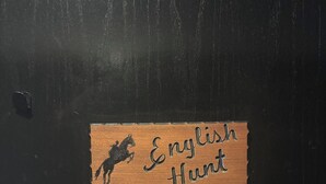 A wooden plaque with a horse silhouette and the words "English Hunt" on a black door. - English Room at Whispering Pines Inn (Norman)