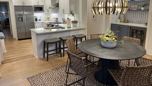 A modern kitchen with white cabinetry, stainless steel appliances, and a central island with bar stools. - Luxury Home - Walk to Grove and Square - Outdoor Patio Seating (Oxford)