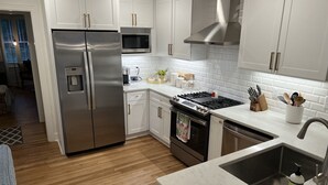 A modern kitchen with stainless steel appliances, white cabinetry, and a marble countertop. - Luxury Home - Walk to Grove and Square - Outdoor Patio Seating (Oxford)