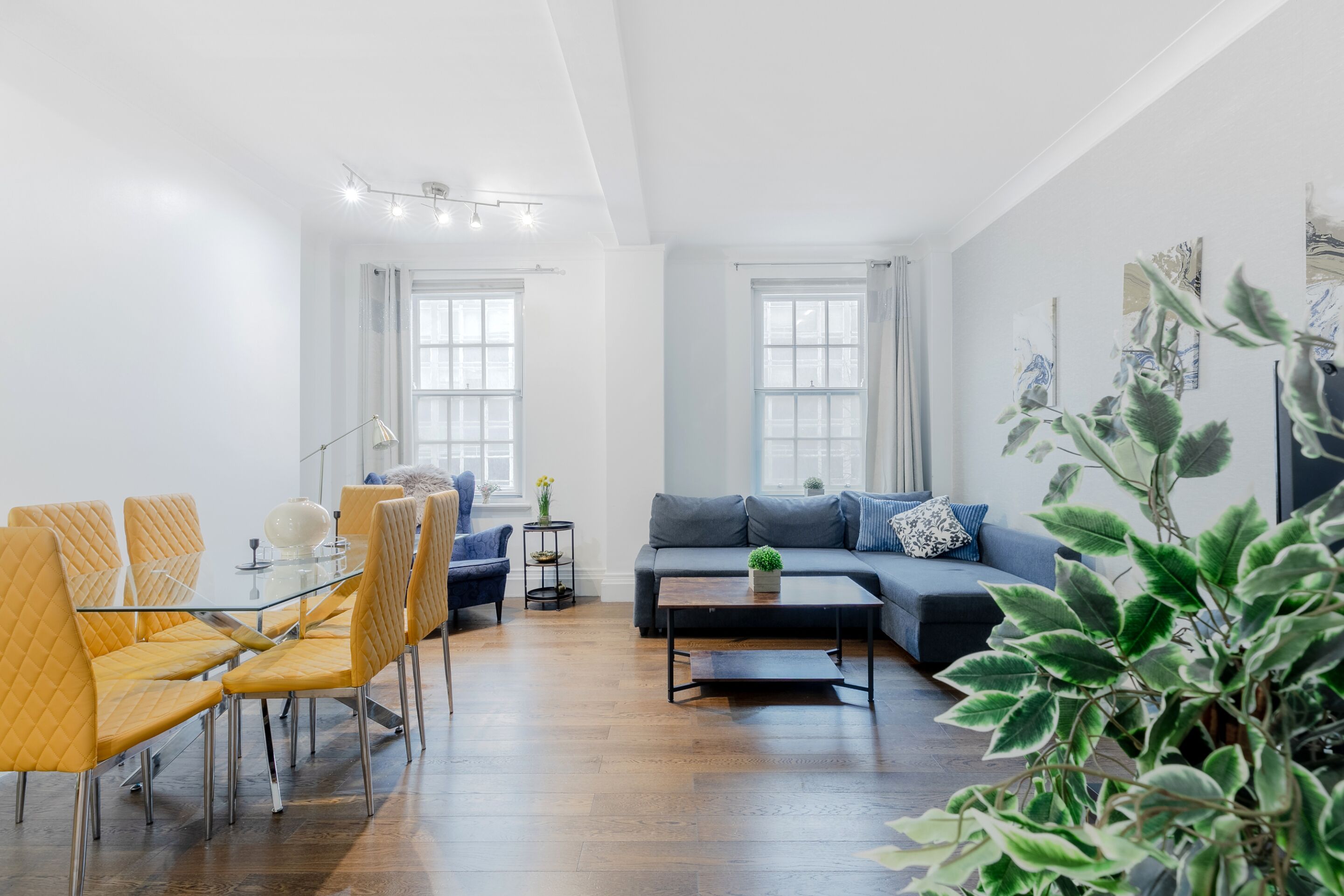 A modern living room with a dining area, featuring a sofa, chairs, a coffee table, and a small side table.
