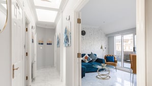 A spacious living area with a blue sofa, a round coffee table, and a large window offering a view of the city. - Marble Arch Apartments (London)