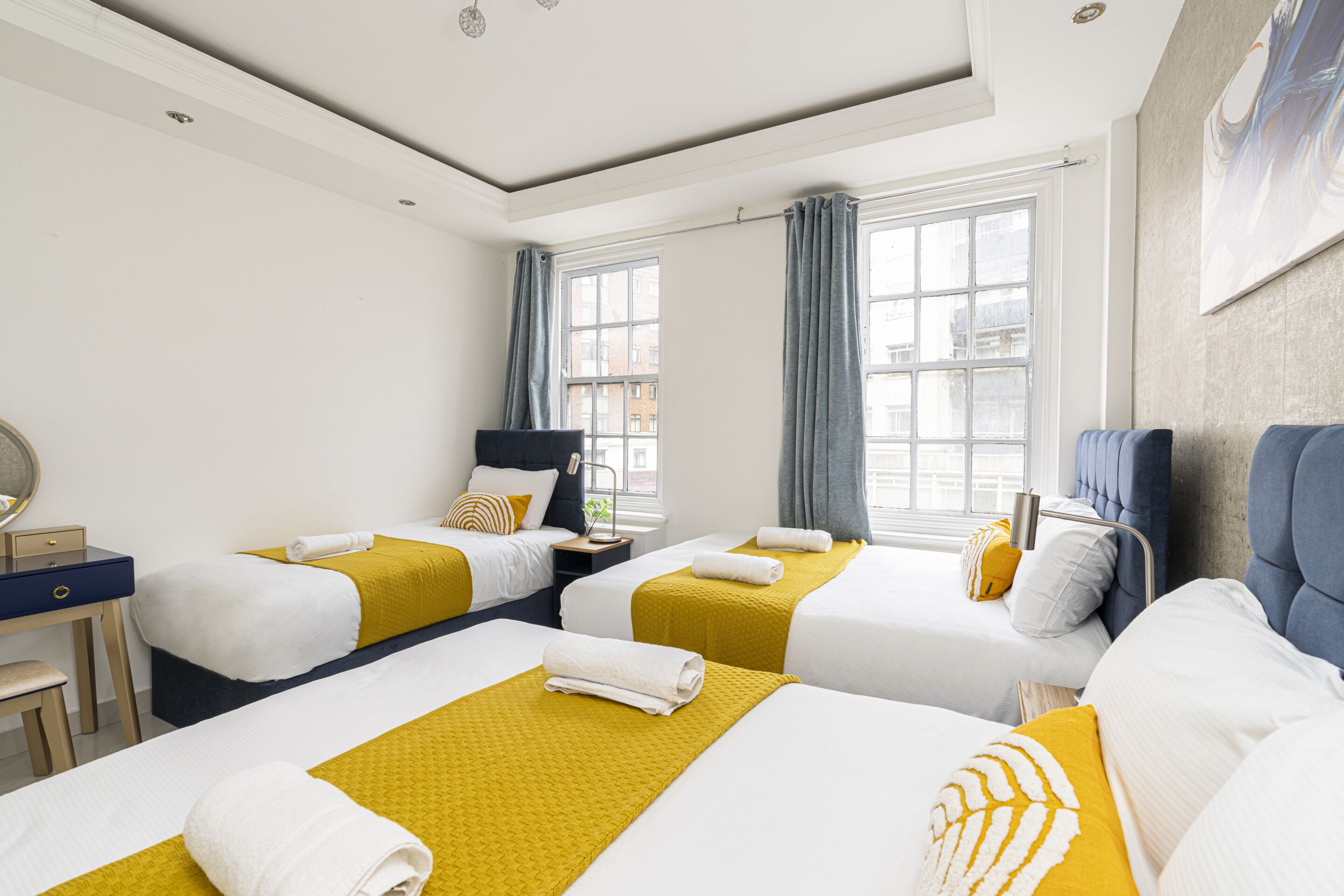 A hotel room with two beds, a desk, and a window with curtains.