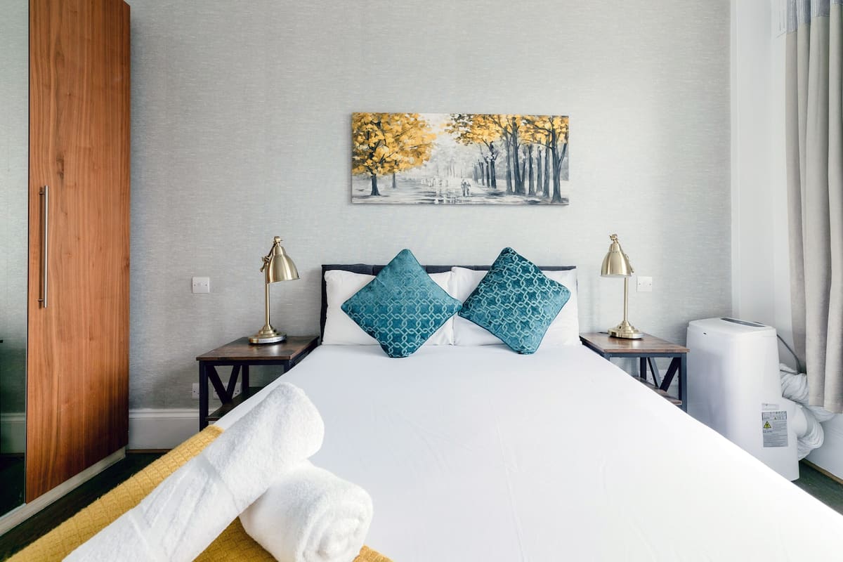 Habitación de hotel con una cama grande, dos mesitas de noche, un cuadro en la pared y un armario de madera.