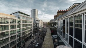 A modern urban street with high-rise buildings, a clear sky, and a sidewalk with pedestrians. - Marble Arch Apartments (London)