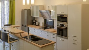 Et moderne køkken med en central ø, rustfrie stålgadgetter og hængende lamper.