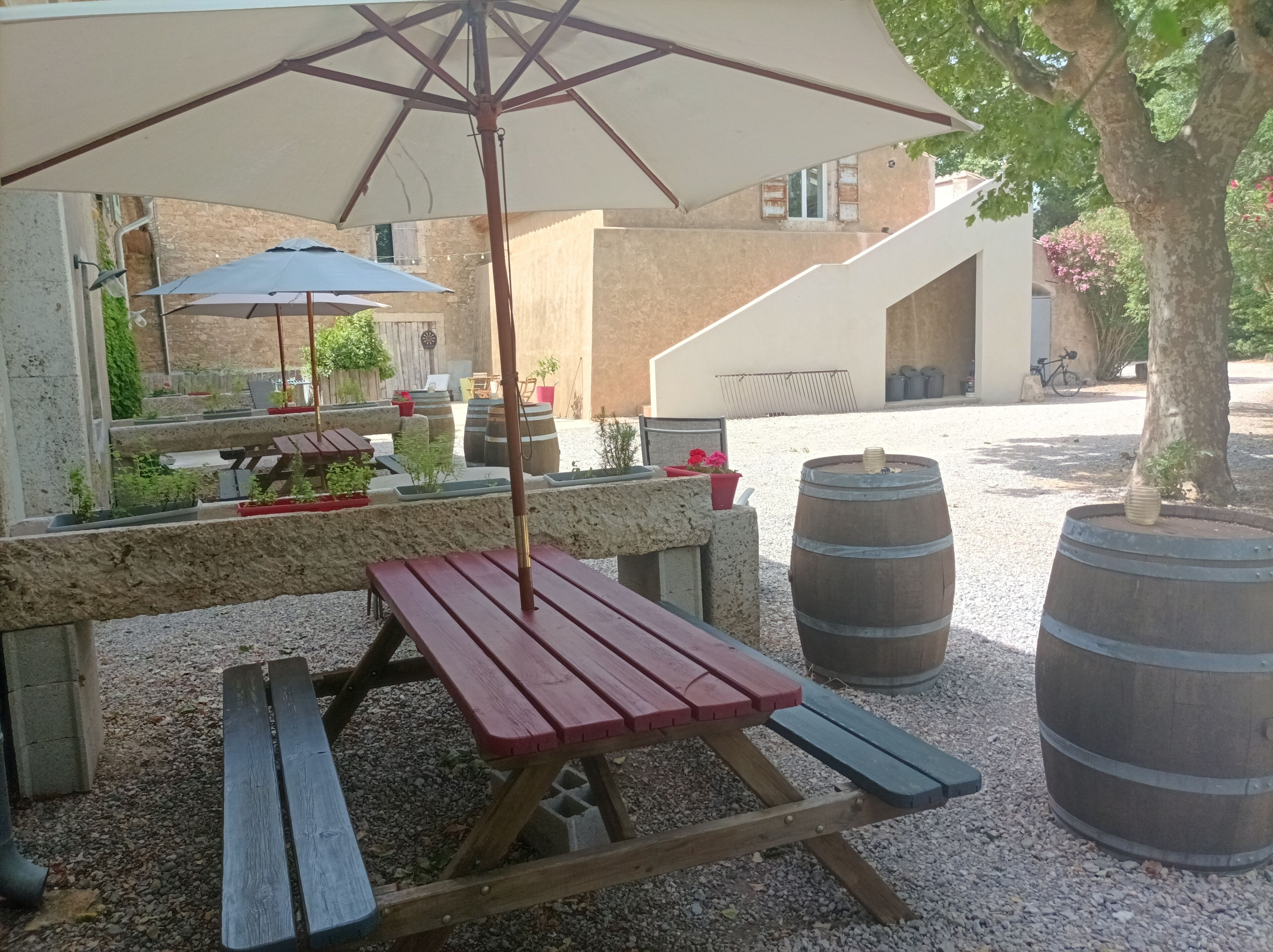 An outdoor seating area with a picnic table, umbrellas, and potted plants.