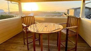 A covered outdoor seating area with a wooden table and chairs, overlooking a residential area.