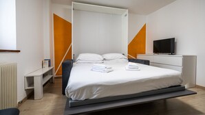 A modern hotel room with a bed, a television, a desk, and a chair. - Italianway - Castellana Mono 68 (Udine)