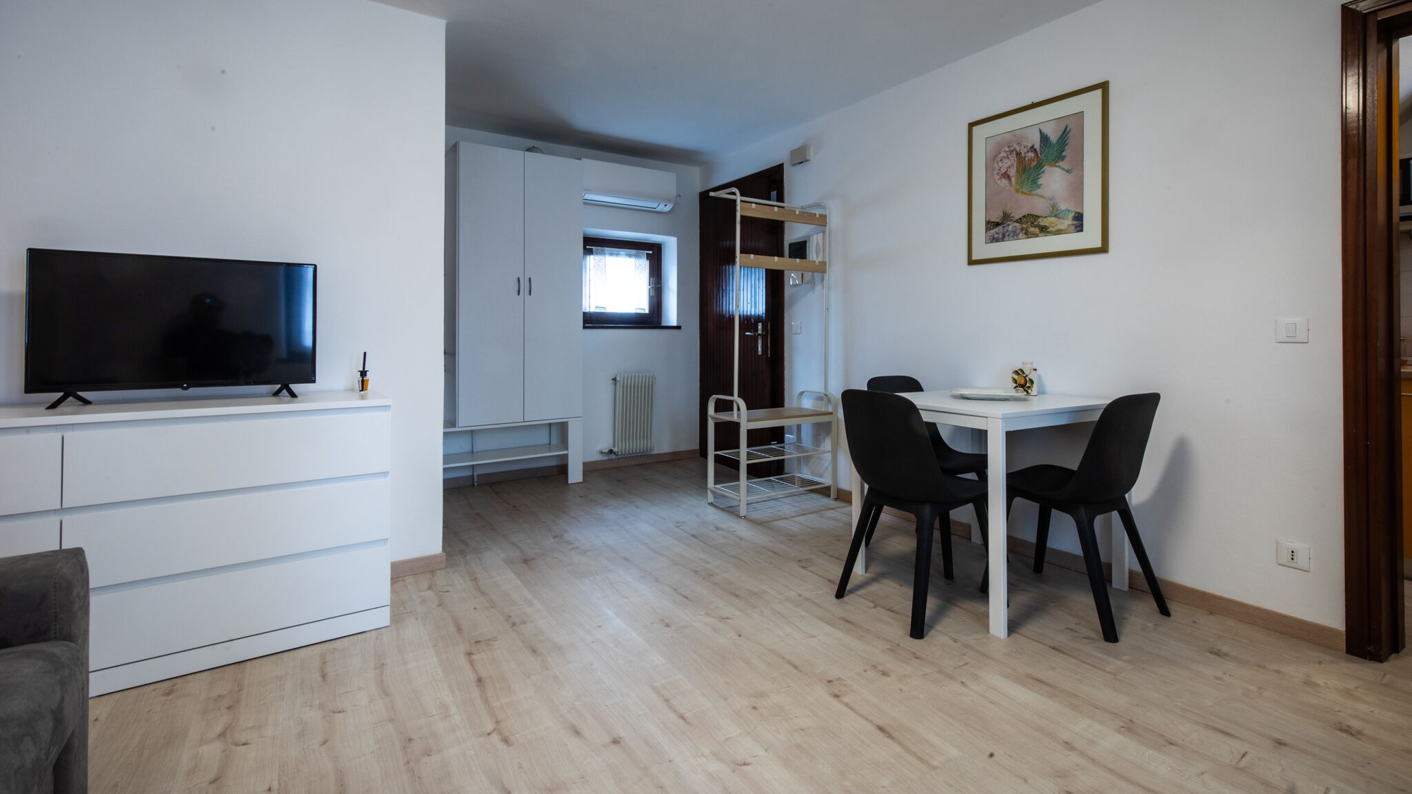 Un salon moderne doté d’un téléviseur à écran plat, d’un coin repas avec une table et des chaises, et d’un lit superposé à l’arrière-plan.