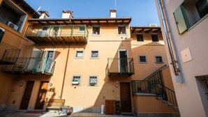 A multi-story building with balconies, a wooden bench, and a staircase. - Italianway - Castellana Mono 68 (Udine)