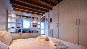 A bedroom with a bed, a wardrobe, and a built-in shelving unit with various items. - Italianway - Galilei 41 (Udine)