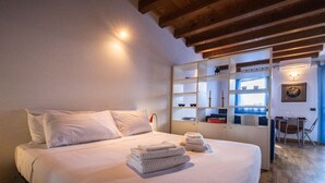 A bedroom with a bed, a bedside table, a shelf unit, and a window. - Italianway - Galilei 41 (Udine)