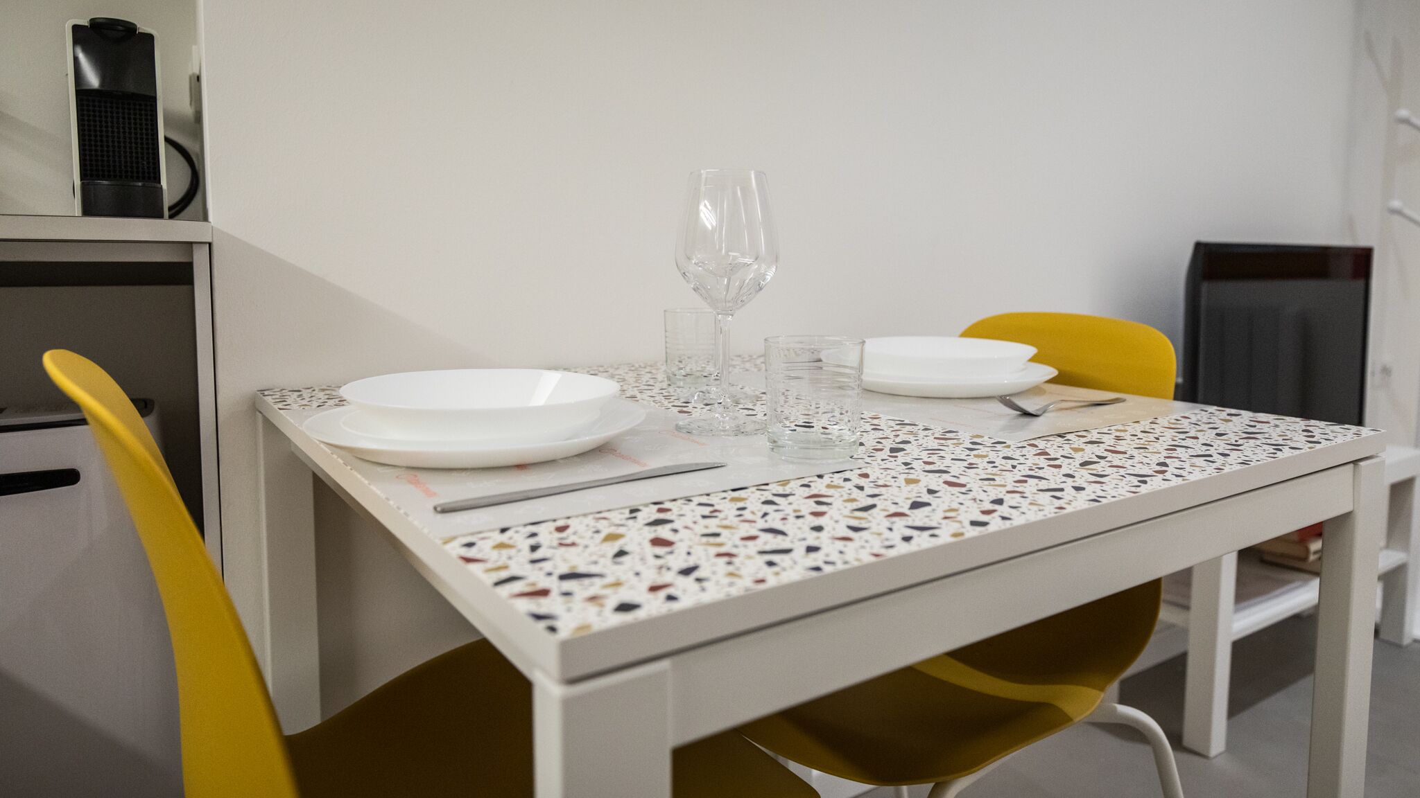 Une table à manger avec des assiettes blanches, des verres transparents et un couteau.