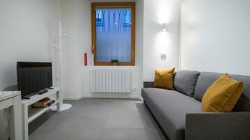 Relax in this stylish living room with a flat-screen TV, comfortable sofa, and a cozy radiator.