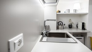 A modern kitchen with a stainless steel sink, a kettle, and a coffee maker on the countertop. - Italianway - Del Sale 4 (Udine)