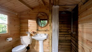 Een houten badkamer in een vakantiehuisje, met toilet, wastafel en douche.