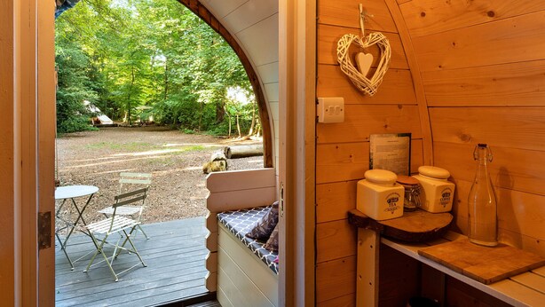 Een gezellig houten chalet met een bankje en tafels op het terras, een decoratie in de vorm van een hart, en een fles op een plank.