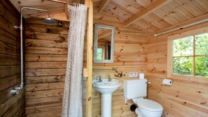 A wooden cabin bathroom with a shower, sink, toilet, and a window. - Bedouin Bell Tent (Woolton Hill)