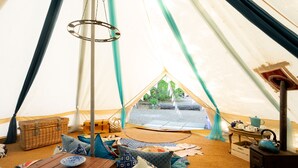 A cozy interior of a tent with a wooden table, cushions, and a kettle.