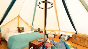 A cozy tent with a bed, pillows, a small table, and a basket.