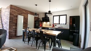 Eine moderne Küche mit Essbereich, mit Backsteinwand, schwarzen Geräten und einem großen Fenster.