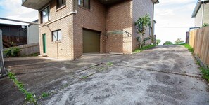 A two-story brick house with a garage door, a fenced yard, and a concrete driveway.