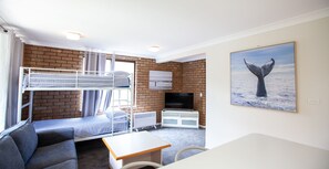 A bunk room with a TV, a painting of a whale, and a view of the sea.