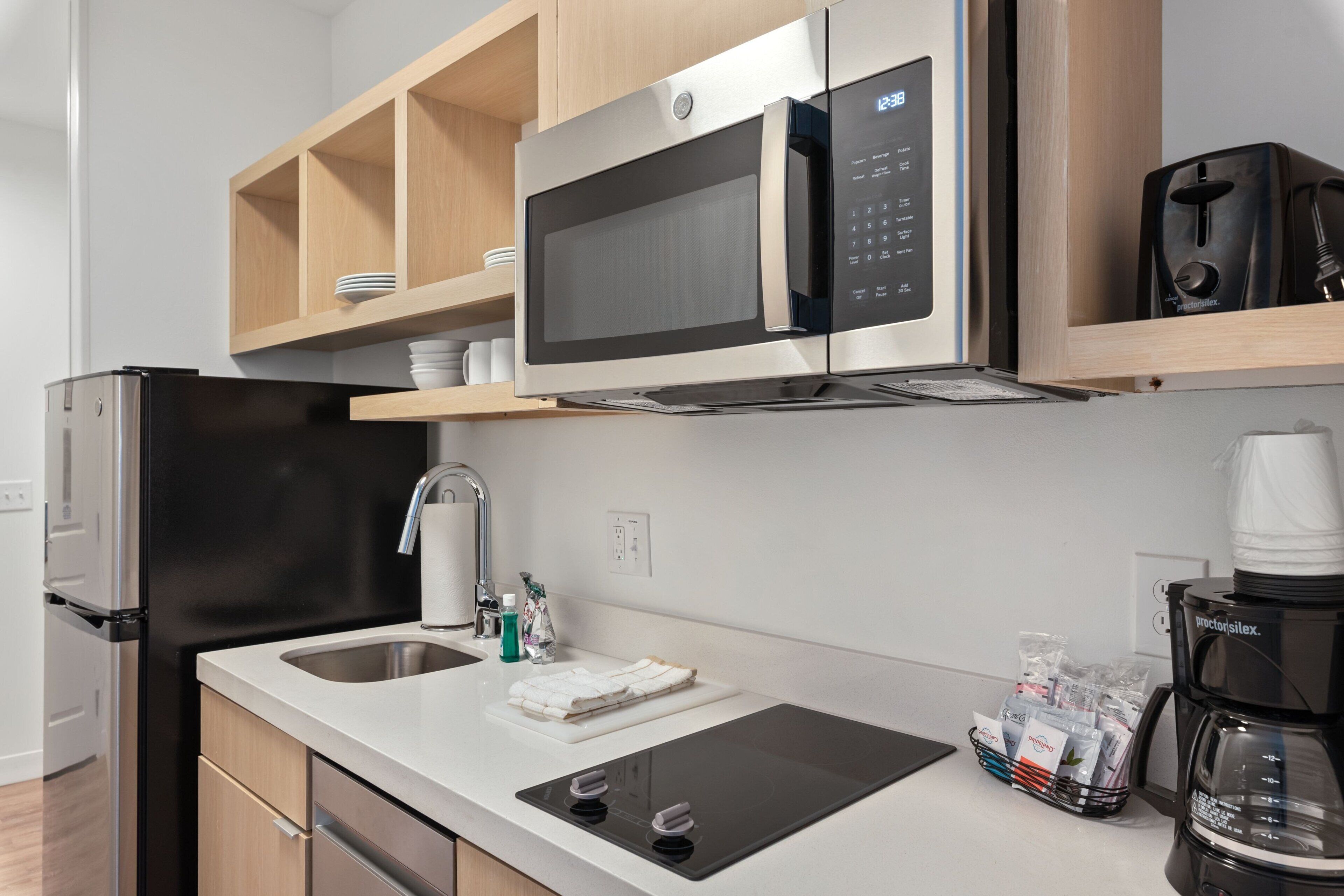 A modern kitchen with a stainless steel microwave, a coffee maker, and a sink.