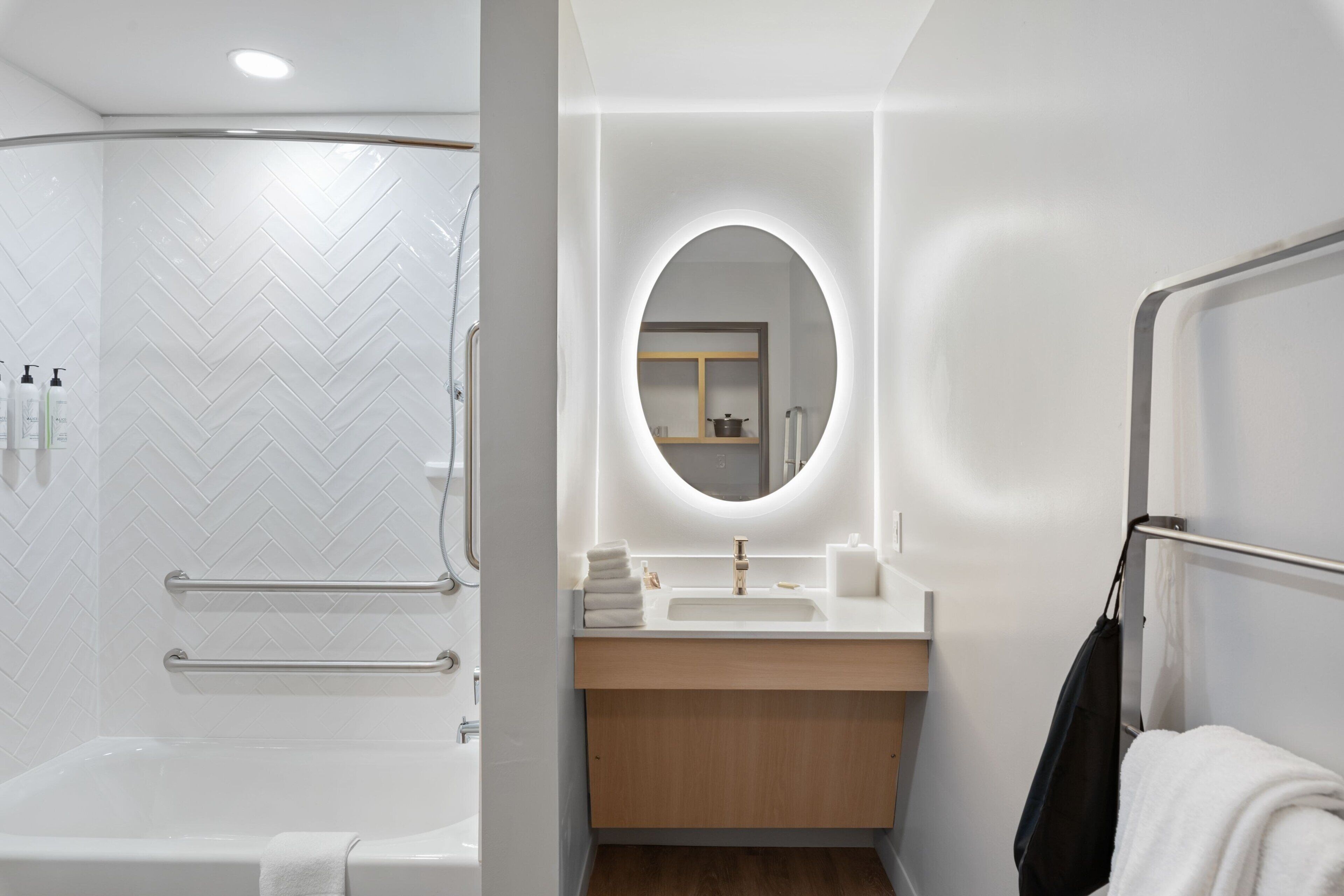 Un baño moderno con ducha, tocador con espejo y perchero.