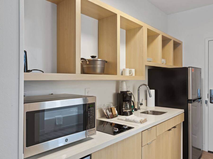 Eine moderne Küche mit einer Edelstahl-Mikrowelle, einer Kaffeemaschine und einem schwarzen Kühlschrank.