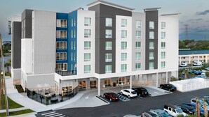 A multi-story hotel with a modern design, featuring a parking lot with several cars and a small outdoor seating area. - Towneplace Suites By Marriott Tampa Clearwater (Clearwater)