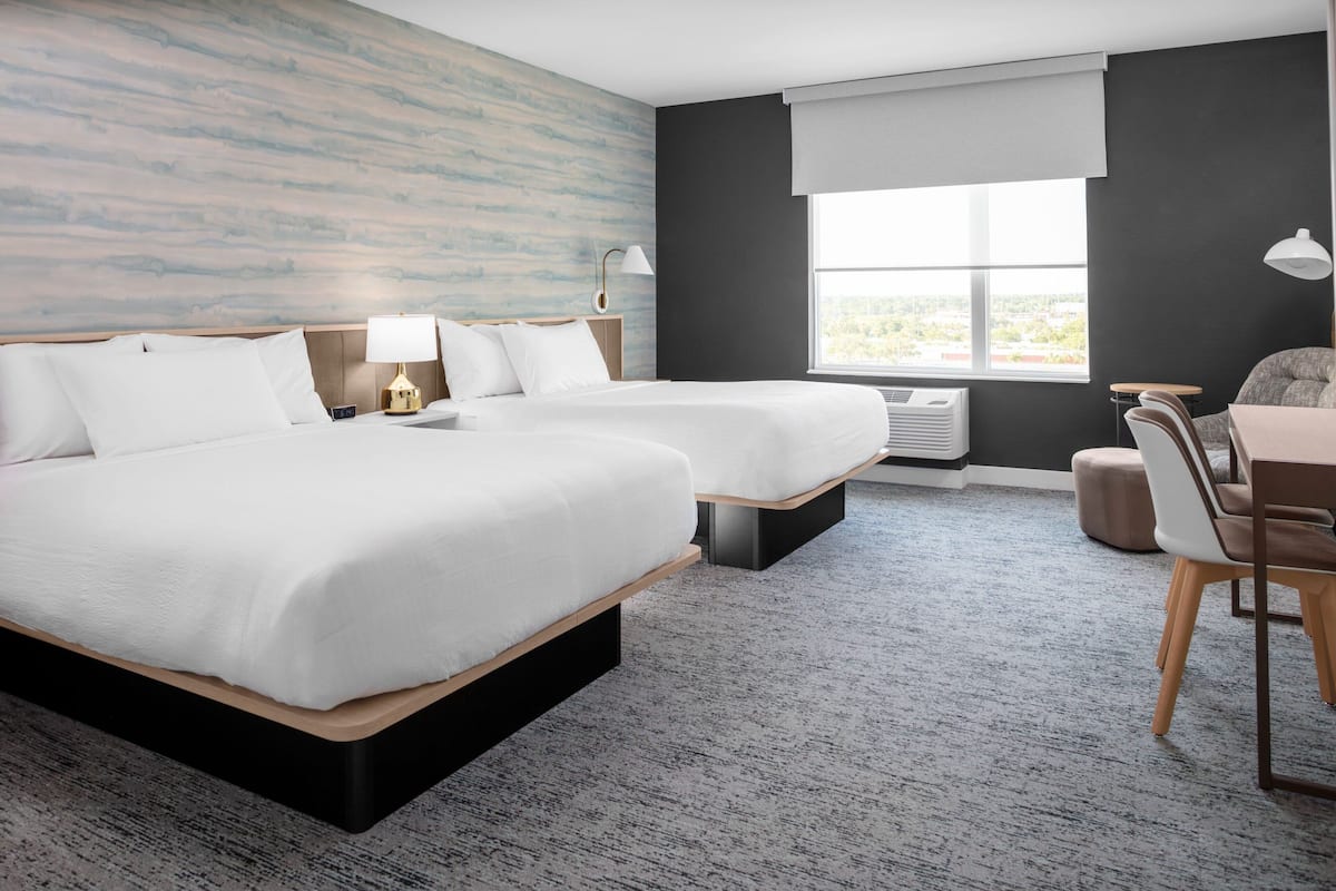Ett hotellrum med två sängar, ett skrivbord och en stol.