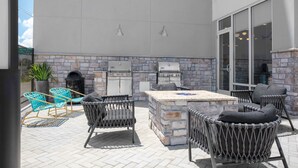 An outdoor patio with stone walls, a grill, and wicker furniture. - Towneplace Suites By Marriott Tampa Clearwater (Clearwater)