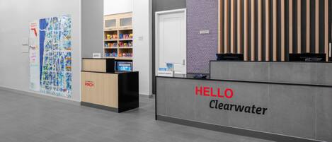 A reception desk with a 'HELLO Clearwater' sign, a map display, and a minibar area.