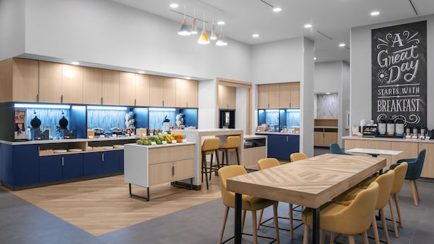 A modern kitchen with a central island, bar stools, and a dining table with yellow chairs. - Towneplace Suites By Marriott Tampa Clearwater (Clearwater)
