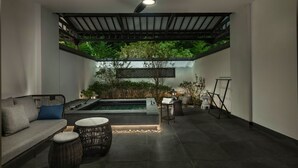 Un espace de détente extérieur moderne, doté d’une piscine, de sièges et d’un ventilateur de plafond.