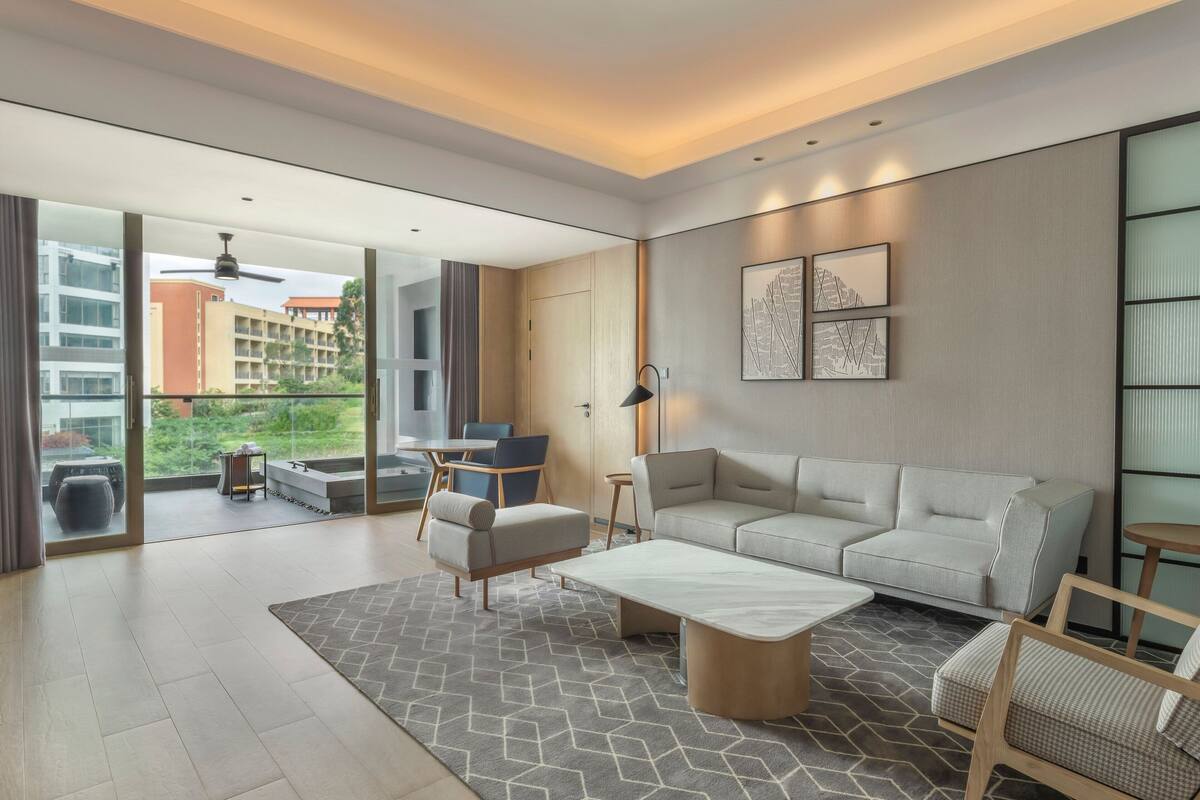 A modern living room with a sofa, armchairs, a coffee table, and a dining area with chairs and a table.