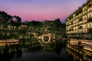 A traditional-style building with a reflection in the water, a bridge, and a pagoda. - Sheraton Maoming Hot Spring Resort (Maoming)
