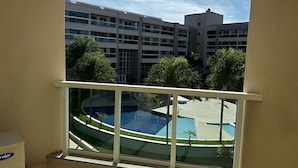 A view from a balcony overlooking a swimming pool and a building complex. - Brisas do Lago - apartamento 2 (Brasília)
