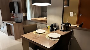 A hotel room with a dining area featuring a table set for two, a coffee maker, and a wine glass. - Brisas do Lago - apartamento 2 (Brasília)