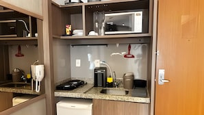 A compact kitchenette with a microwave, coffee maker, and a small sink. - Brisas do Lago - apartamento 2 (Brasília)