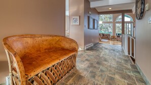 A wooden bench in a hallway with stone flooring and a view of outdoor seating. - Marble Canyon 3 Bdrm|Sleeps 8 (12 inc kids): Unit 102P1 (Fairmont Hot Springs)