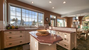 A spacious kitchen with large windows, a central island, and a dining area with outdoor seating. - Marble Canyon 3 Bdrm|Sleeps 8 (12 inc kids): Unit 102P1 (Fairmont Hot Springs)