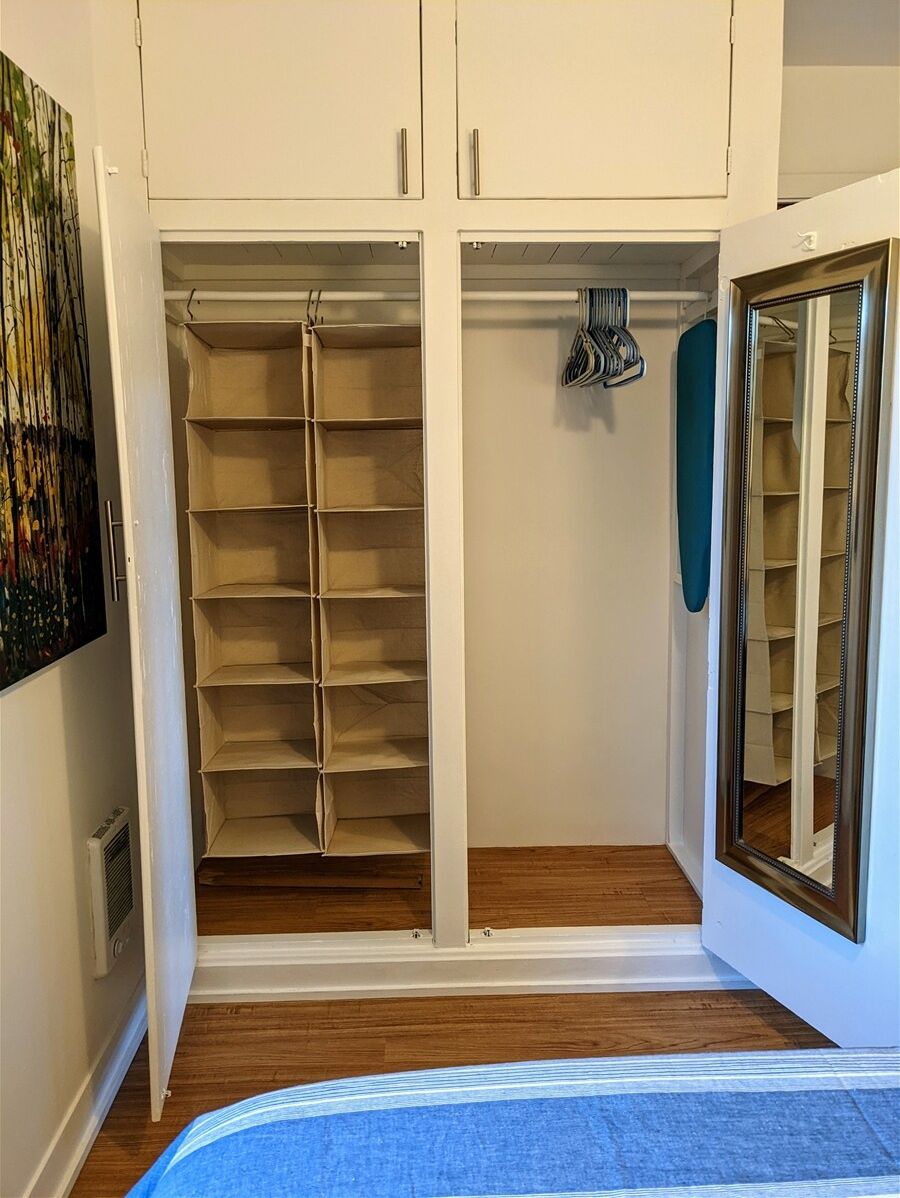A walk-in closet with open shelving, a hanging rod, and a mirrored closet door.