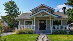Een tweelaags huis met een veranda, een pad van stenen dat naar de ingang leidt en een verzorgd gazon.